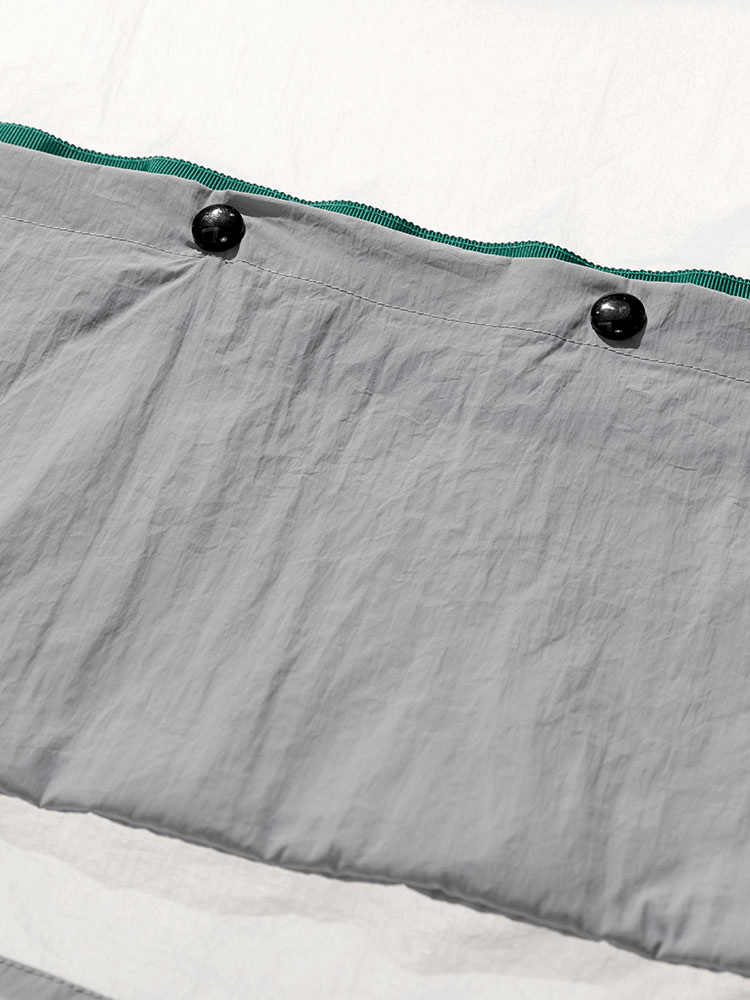 Ultra-light windbreaker detail showing buttoned waterproof material, part of multi-pocket design with nylon lining.